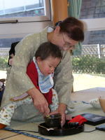 幼児の手をとってお茶をたてる和田典子さん。