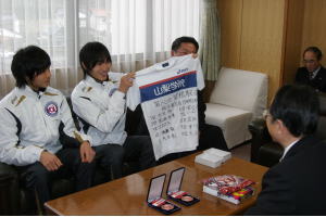 箱根駅伝総合3位のメダルやユニホームを速水市長に見せて、大会を振り返る山梨学院大学4年の双子ランナー、大谷健太さん（左）と康太さん（左から2人目）。