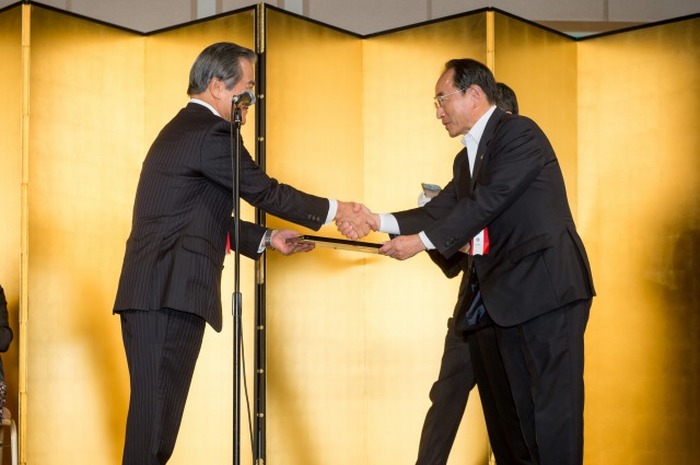 小宮山会長から第1回プラチナ大賞特別賞の表彰状を受け握手する速水市長（2013年7月）