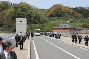 市道北原本郷線のダム堤頂を歩く参加者