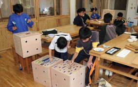 中学校で多目的に使われる立方体の箱を製作する参加者