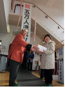5万人目の鳥谷怜子さんに宮川会長から記念品が手渡されました