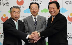 協定書の調印を終え、三者が握手している様子