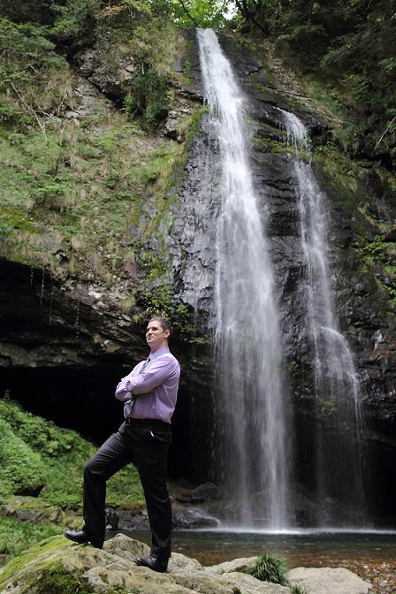 龍頭が滝の前に立つダニエルさんの写真