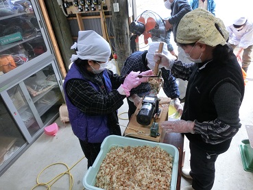 教わりながら味噌づくりをする写真