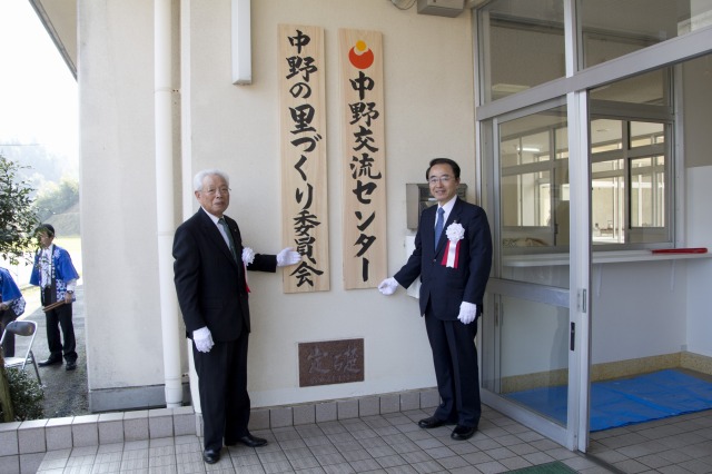 看板を掛ける深石会長と速水市長